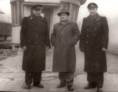  Dvaja muži v železničných rovnošatách, jeden v civile pred stanovišťom perónneho výpravcu na lamačskom zhlaví v Bratislave hl. st. Anonym, cca 1960. 180 x 130 