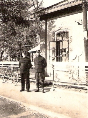  Dvaja muži v železničných rovnošatách pred rohom starej budovy žst. Senec. text: Albert Kopecký (vpravo), prednosta žst. Senec do r. 1935, vedľa výpravca stanice p. Hein. Anonym, 1932. 82 x 60. 