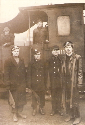  Skupina mužov v železničných rovnošatách a v pracovnom pred kabínou parného rušňa radu 411.0. Anonym, cca 1950. 110 x 80 