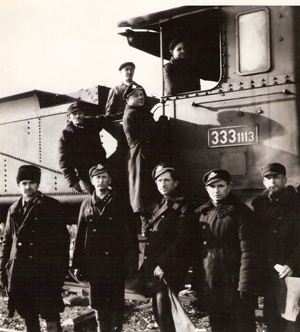  Skupina mužov v železničných rovnošatách a v pracovnom pri kabíne parného rušňa 333.1113. Text: Žst. Leopoldov. Anonym, cca 1950. 125 x 135 