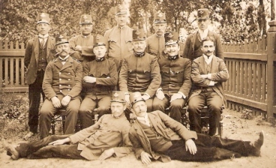  Dvanásť mužov v rakúskych železničných rovnošatách a v civile, v pozadí ozdobný drevený plot. Anonym, cca 1900. 140 x 90 