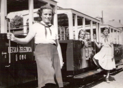  Tri pionierky pri vozňoch pionierskej železnice. Text: Odovzdávanie detskej železnice v dielňach ČSD v Trnave. Anonym, cca 1950. 162 x 116 