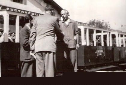  Dvaja muži v civile a jeden v pracovnom pred vozňami pionierskej železnice. Text: Odovzdávanie detskej železnice v dielňach ČSD v Trnave. Anonym, cca 1950. 172 x 120 