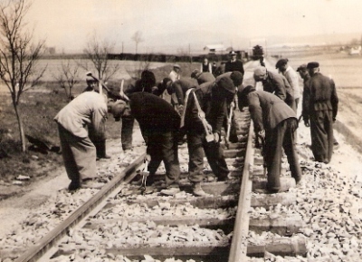  Skupina robotníkov pri ručnom podbíjaní trate. Text: Pracovné brigády železničiarov na stavbe Trate Mieru, Lučenec - Opatová. Anon., cca 1950. 115 x 85 